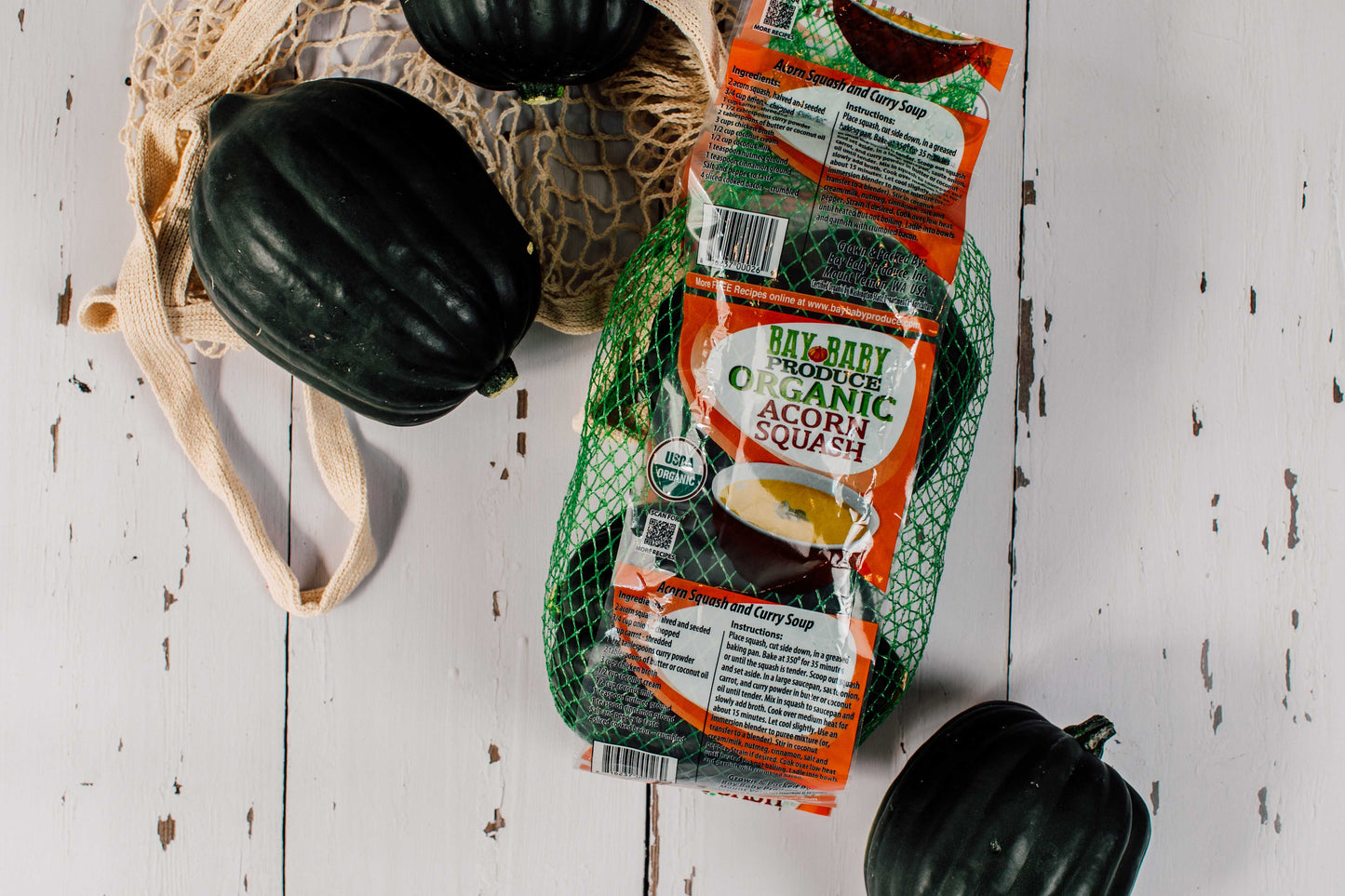 Packaged organic acorn squash with fresh squash on a wooden surface