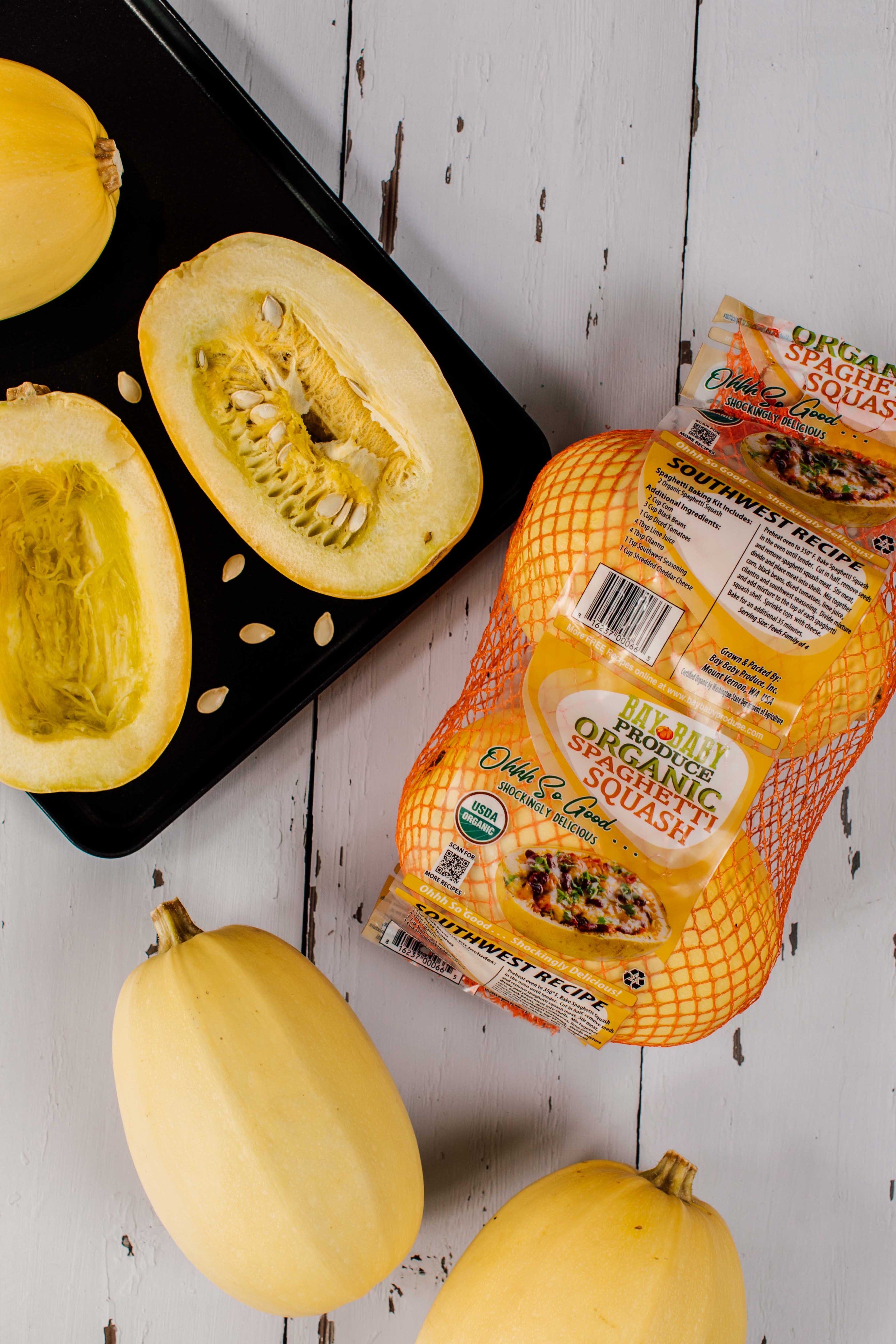 Spaghetti squash halves on a baking tray with a package of Organic Valley organic whole milk.