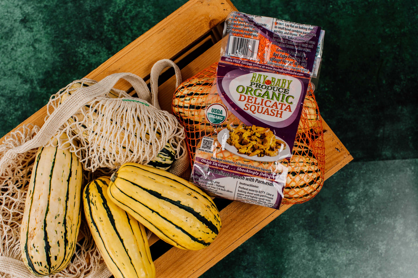 Packaged organic delicata squash on a wooden board with fresh squashes.