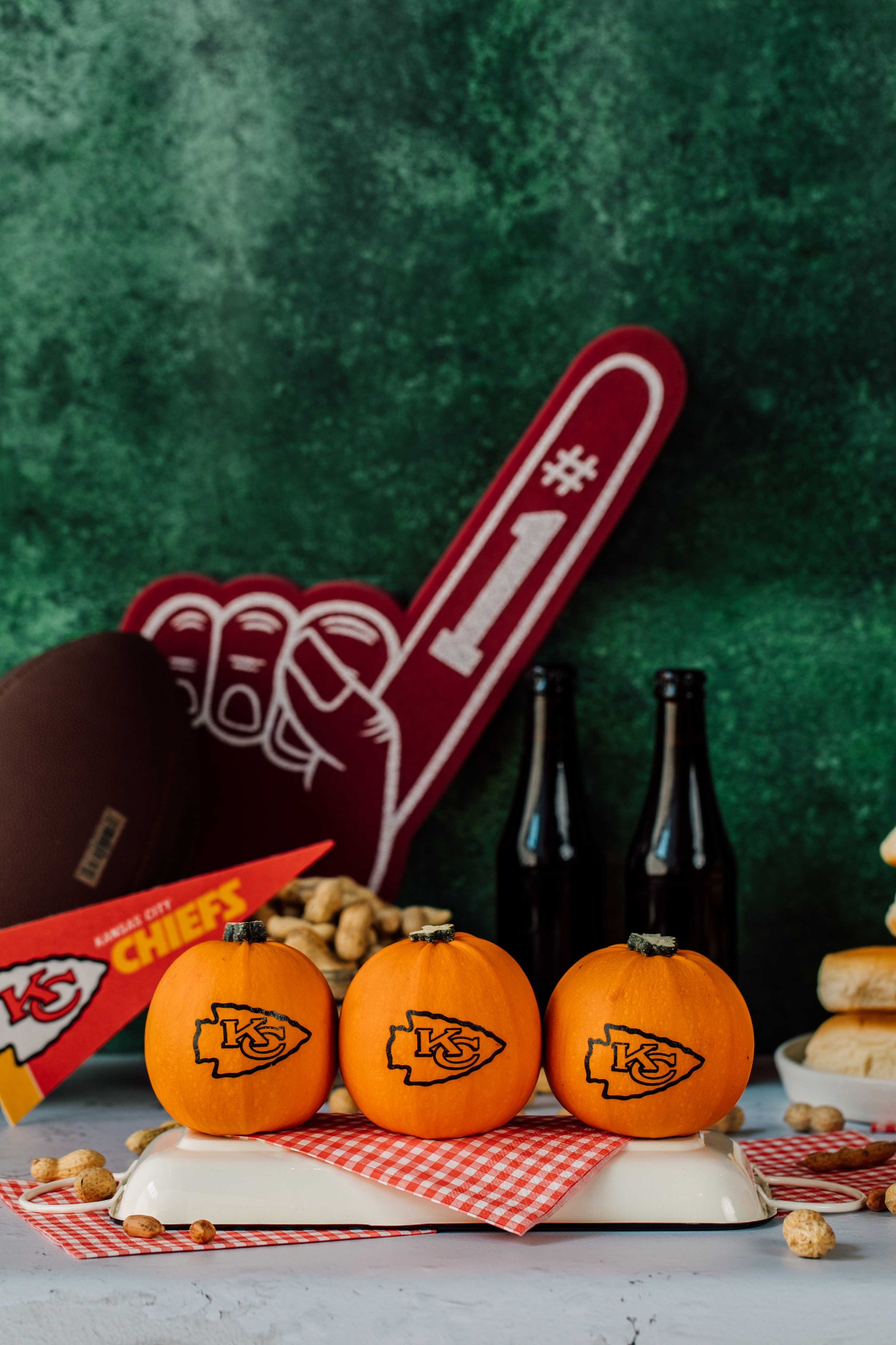 Three small pumpkins with K's logo on a platter with beer bottles and a large number one sign in the background.