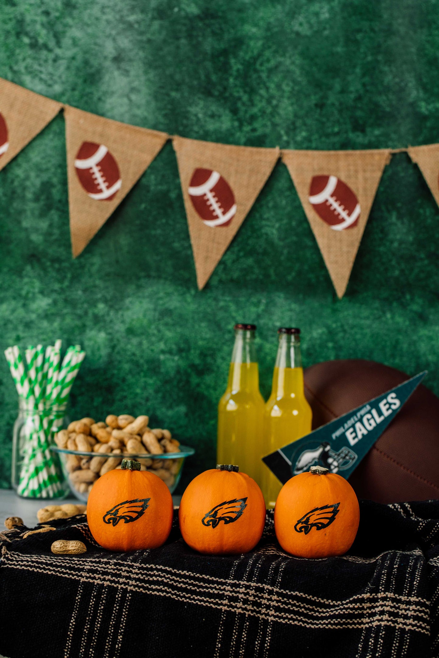 Table setup with sports-themed decor, including pumpkins, bottles, and a banner on a green background.