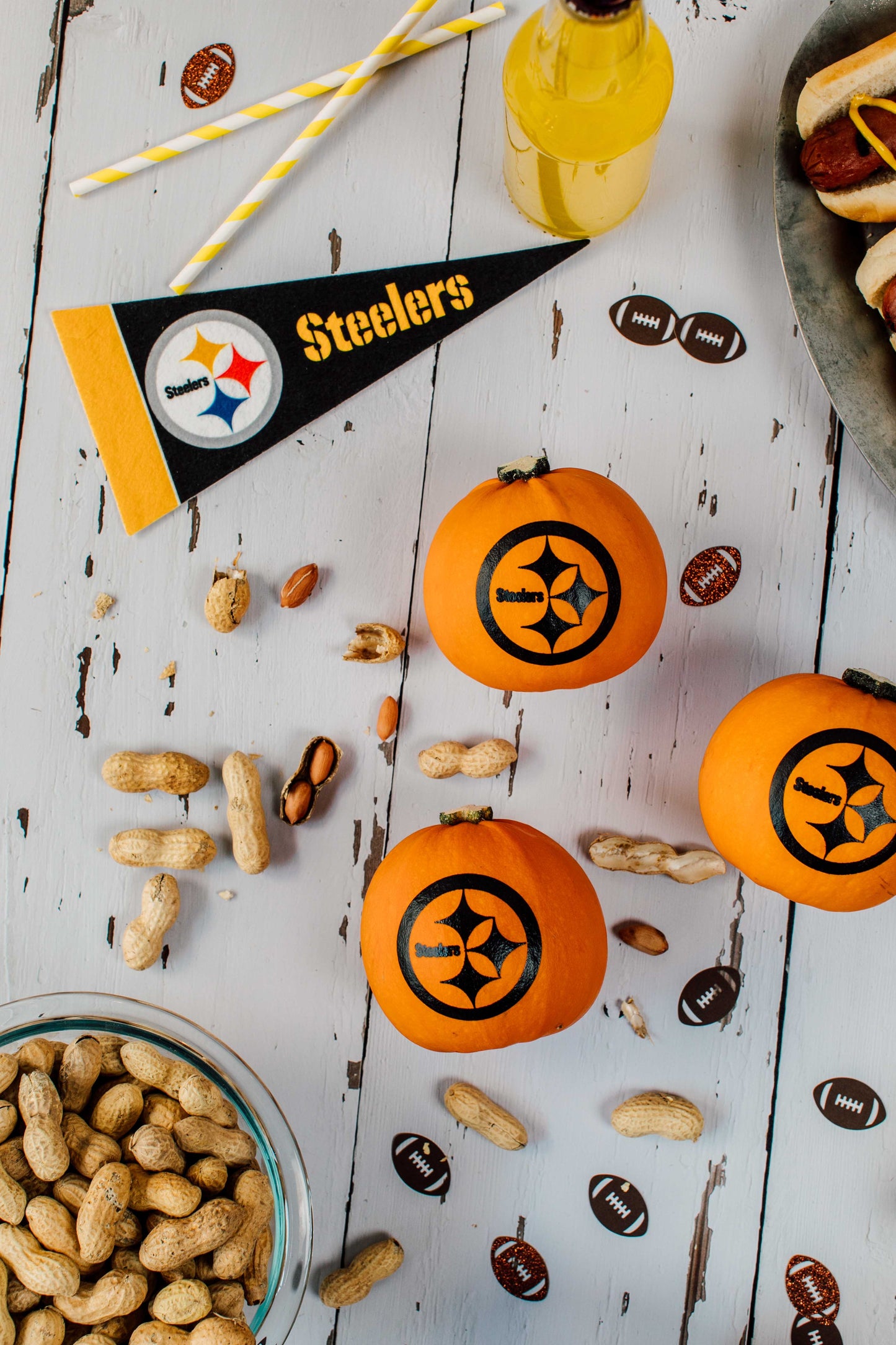 Pumpkin decorations with Steelers logo on a table with snacks and a banner.
