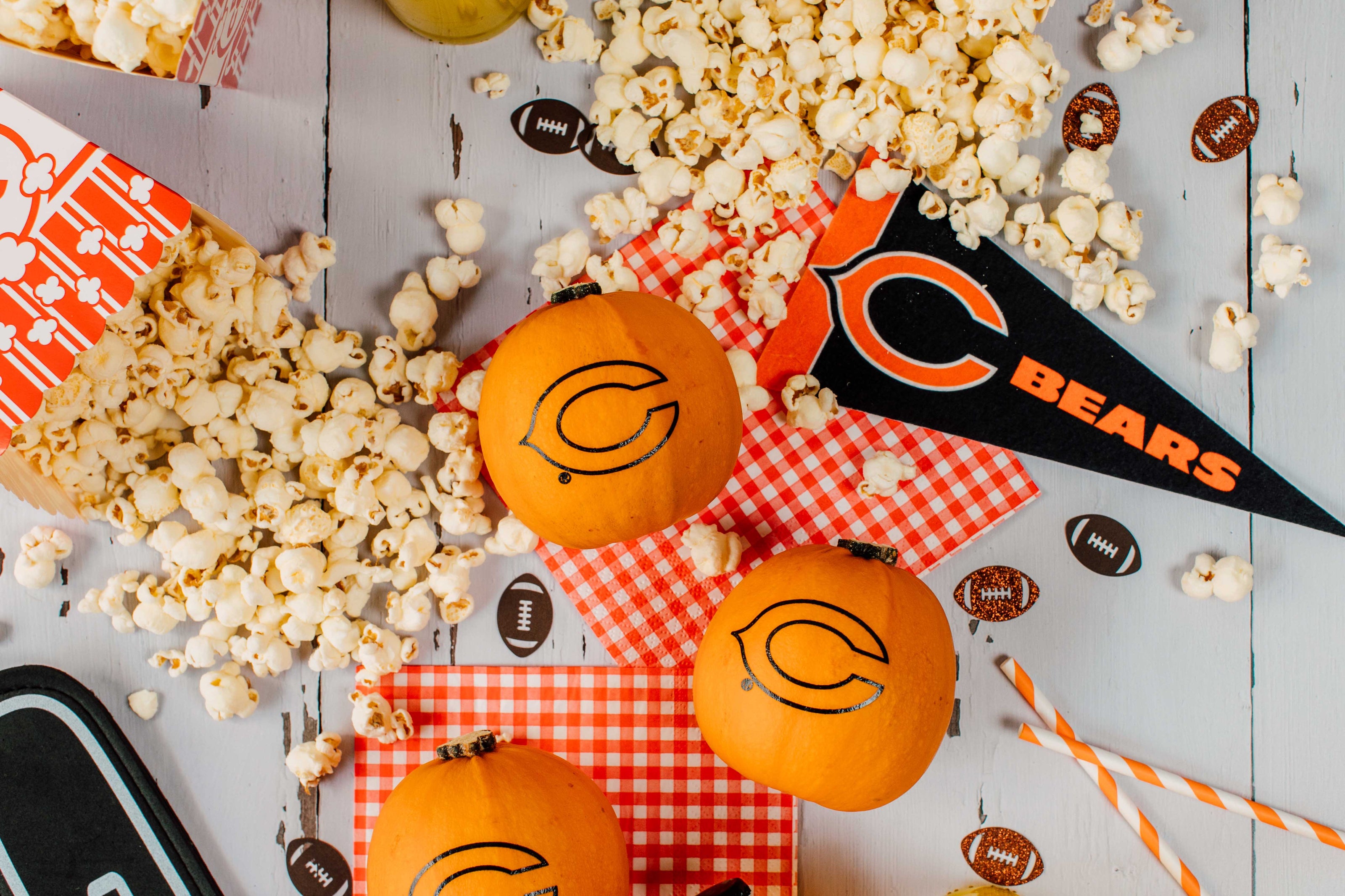 Popcorn, pumpkins, and a 'Bears' flag on a wooden surface with decorative elements.